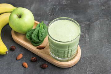 Green detox smoothie in a glass, blended vegetarian drink from spinach leaves, apple, banana fruit...