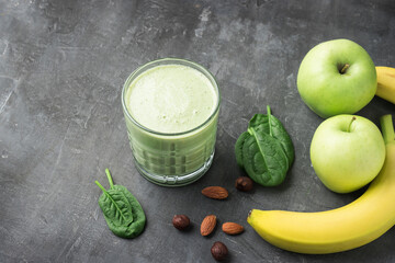 Green detox smoothie in a glass, blended vegetarian drink from spinach leaves, apple, banana fruit...