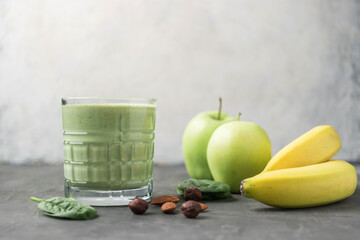 Green detox smoothie in a glass, blended vegetarian drink from spinach leaves, apple, banana fruit...