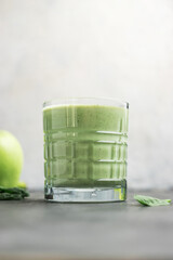 Green detox smoothie in a glass, blended vegetarian drink from spinach leaves and apple, healthy...