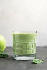 Green detox smoothie in a glass, blended vegetarian drink from spinach leaves and apple, healthy eating concept