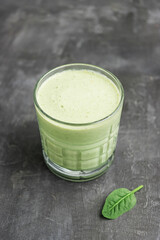Green detox smoothie in a glass, blended vegetarian drink from spinach leaves on dark background,...
