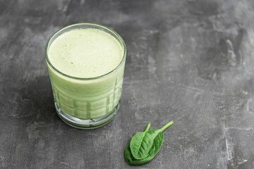 Green detox smoothie in a glass, blended vegetarian drink from spinach leaves on dark background,...