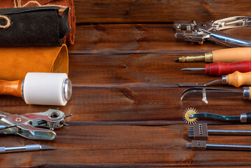 Leather and leather craft work tools instruments on the old wooden workbench flat lay background...