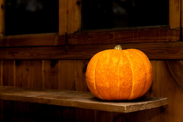 an orange pumpkin lies on a rack in a dark barn.