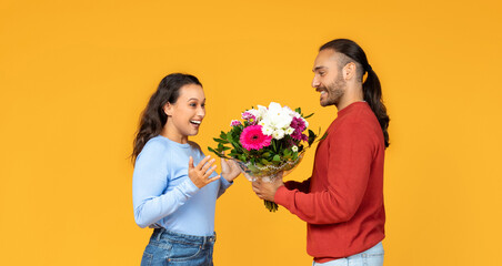 Fototapeta na wymiar Two cheerful people loving couple exchange bouquet of mixed flowers