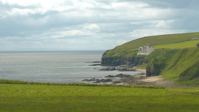 Seagulls circling over beautiful Dunbeath Castle, built on a grassy cliff top overlooking North Sea. Magnificent old building defying constantly changing weather on the north coastline of Scotland.