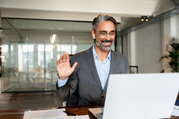 Middle-age Hispanic man using computer remote for business studying, watch online virtual webinar training meeting, video call. Smiling mature Indian or Latin businessman working on laptop in office.