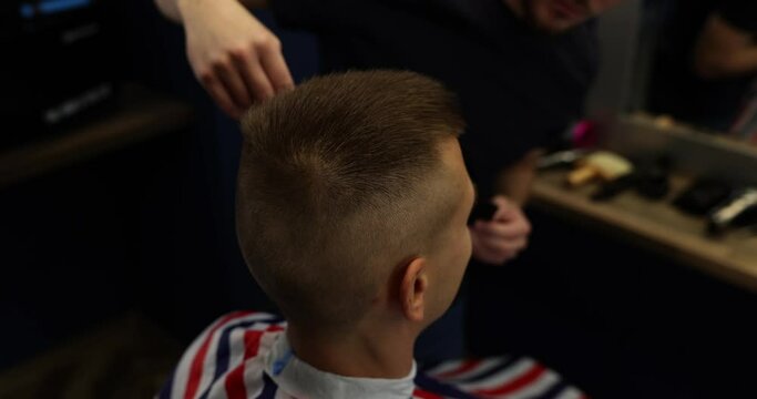 Barber trims hair in temporal area of man client head
