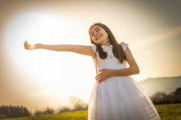 Smiling girl happily celebrating her first communion in a natural and sunny environment