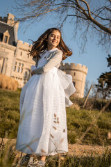 Obraz premium Smiling girl happily celebrating her first communion in a natural and sunny environment