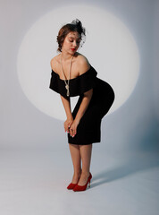 An elegant young woman in retro-style clothes poses in full height.