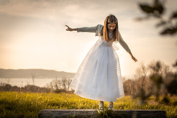 Girl in a dress celebrating her first communion while playing in a beautiful park with the sea in...