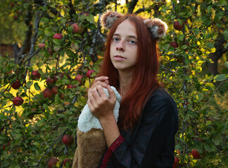 Selfie portraits of a red-haired woman with a fluffy tail and ears in the summer outdoors in an...