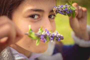 Close-up of the eyes of a girl looking through some flowers she is playing with