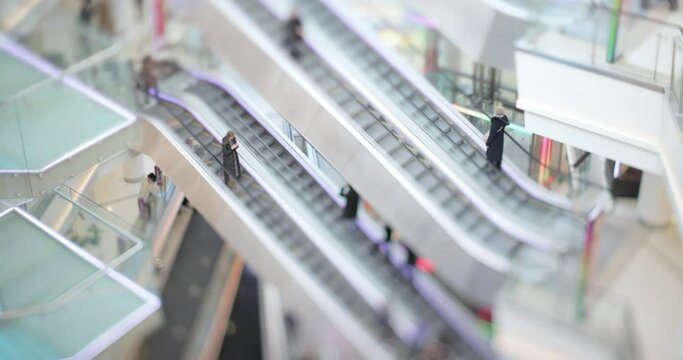 People in motion in escalators at the modern shopping mall. Tilt shift lens shooting with super shallow depth of field.