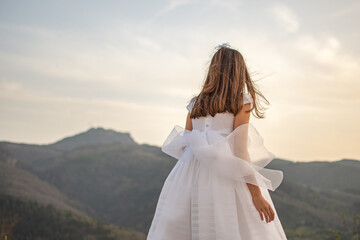 Fototapeta na wymiar Girl with first communion dress observing the mountain