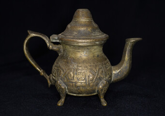 Antique metallic teapot isolated in black background 