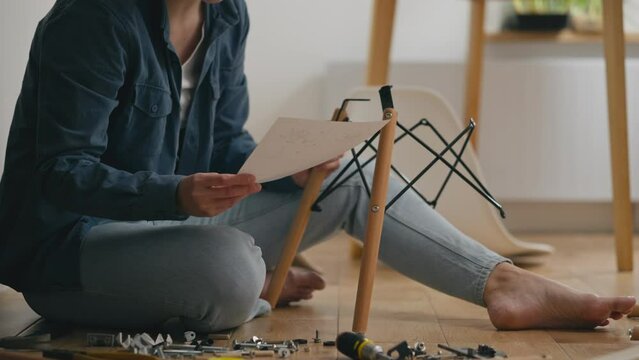 A girl who has just moved to a new home is assembling furniture on her own. A close-up shows her decisive action as she puts the pieces of the chair together