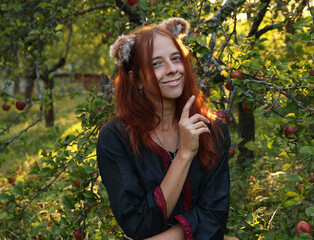 Selfie portraits of a red-haired woman with a fluffy tail and ears in the summer outdoors in an...