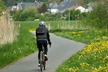Radfahrer in langer Radbekleidung auf einem Crossfahrrad auf einem asphaltierten Radweg im Frühjahr