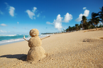 Caribbean Christmas Snowman made out of sand on sandy beach. Holiday vacation in hot countries concept. New Year travel greeting card with copy space.