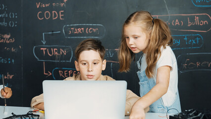 Closeup of boy using laptop programing engineering code and writing program while group of diverse...