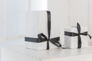 Packaging box studio shot of white boxes wrapping with black ribbon with bowknot on white background. Black Friday sale. shop sale promotion and anniversary celebration concept