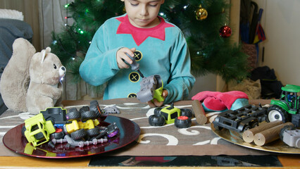 Cute boy elf assembling toys for kids in front of Christmas tree. High quality photo