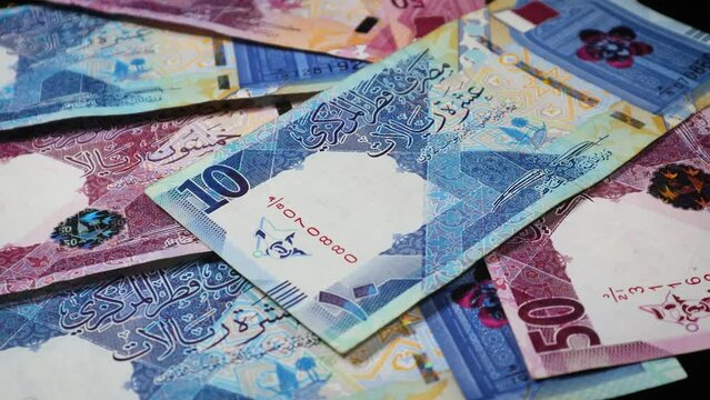 A slow-motion closeup of the security features of Qatar's banknotes of different denominations.