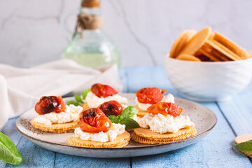 Bruschetta on crispbread with ricotta and baked tomatoes on a plate on the table