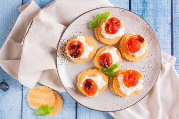 Close up of bruschettas on crispbread with ricotta and baked tomatoes on a plate top view