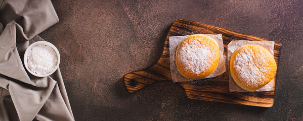 Fresh donuts with powdered sugar and sweet filling on a plate on the table top view web banner - obrazy, fototapety, plakaty