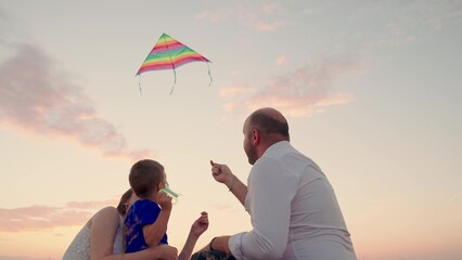 Family love concept. Family with son play together in the park in summer, fly a kite into the sky....