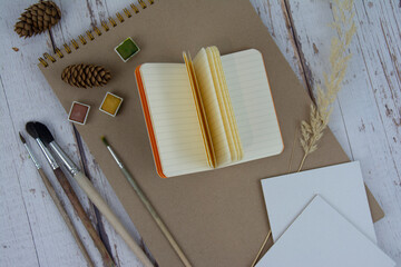 The artist's accessories on a wooden table, top view. A workplace for creativity. Sketchbook, notepad, brushes, paints.