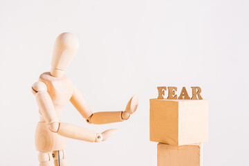Fear concept wooden man and word fear on light background