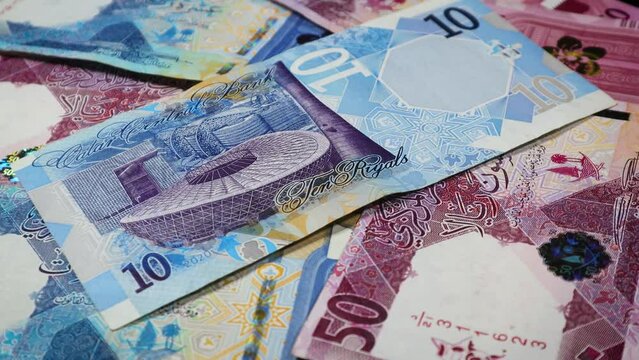 A macro level closeup and slow-motion shot of Qatar's banknotes, in different denominations while rotating on a display stand.