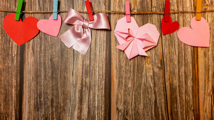 Decorations concept for Valentine's Day, Mother's Day. Top view photo of paper hearts hanging on wooden hooks against a wooden background isolated with copyspace