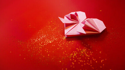 Arranged origami paper hearts on a red background with golden glitters, decorations for Valentine's...