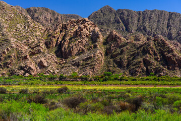 The green valley of the Rio Colorado backed by rocky mountain ridges near the village of...
