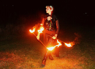 Selfie portraits of a red-haired woman in a shiny gothic outfit, with horns and burning torches...