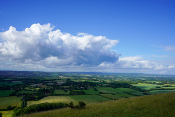 Obraz premium Views over countryside farm fields with clouds in blue sky in the summer