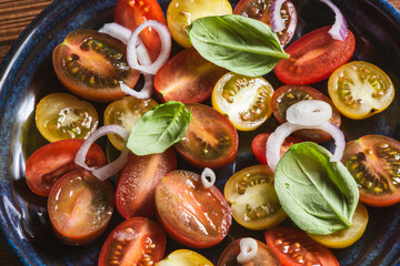 Salad with halves of red and yellow tomatoes cherry with basil, topping balsamic sauce on white...