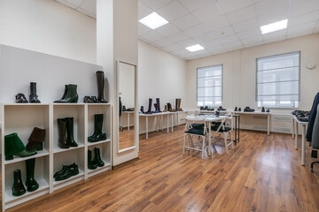 A spacious showroom room with light walls, shelves for shoes and a large mirror.