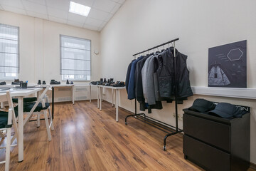 A modern showroom with clothes on a hanger, shoes on the shelves.