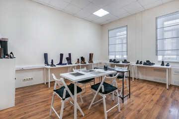 A view of a modern showroom in bright colors with shoes on the shelves and a table for visitors.