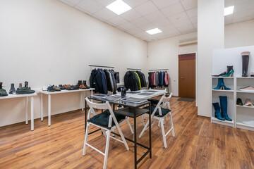 The interior of a spacious showroom with light walls and furniture for displaying clothes .and shoes.