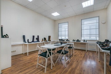 Modern showroom with light walls, brown floor and tables with shoes placed.