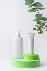 Minimalism style composition with white unbranded cosmetic tube and bottle with dropper on bright green cosmetic podium on white background. Cosmetic sale and promo banner, copy space for your design.