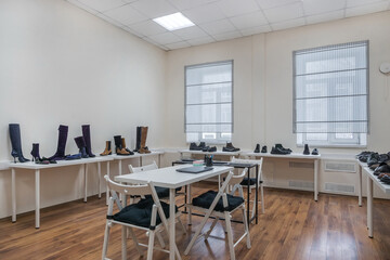 A bright showroom room with windows. Shoes are placed on tables along the walls.